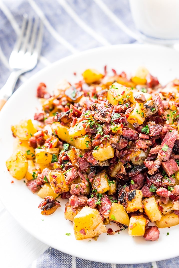 Corned Beef Hash on white plate with fork and blue striped napkin