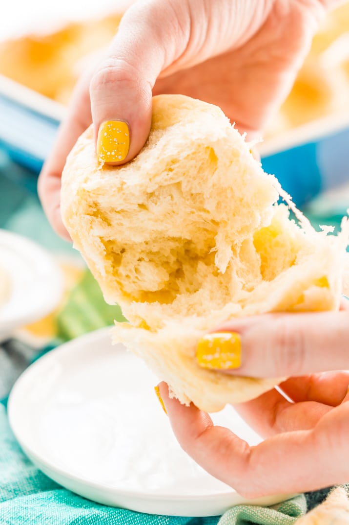 Woman's hands pulling apart a yeast roll