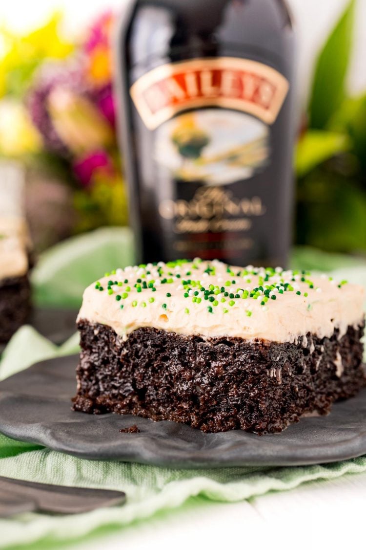 Close up photo of Irish Cream Cake on a black plate with a bottle of Bailey's in the background.