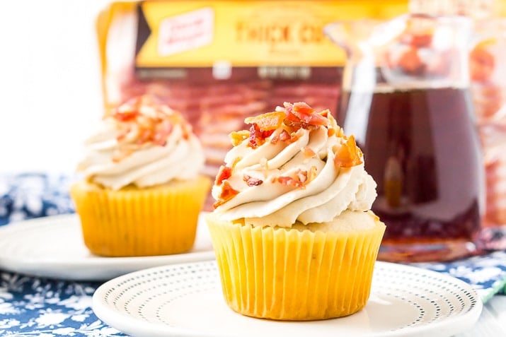 Maple Bacon Cupcakes on plate with syrup dispenser and package of bacon