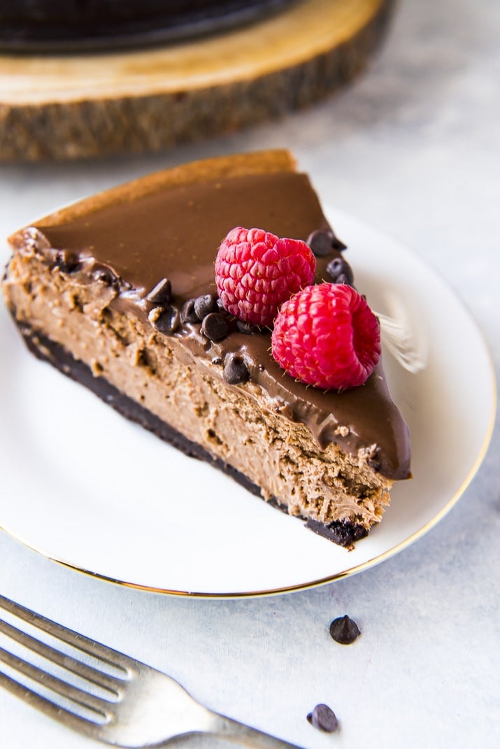 Chocolate cheesecake recipe with raspberries on white plate