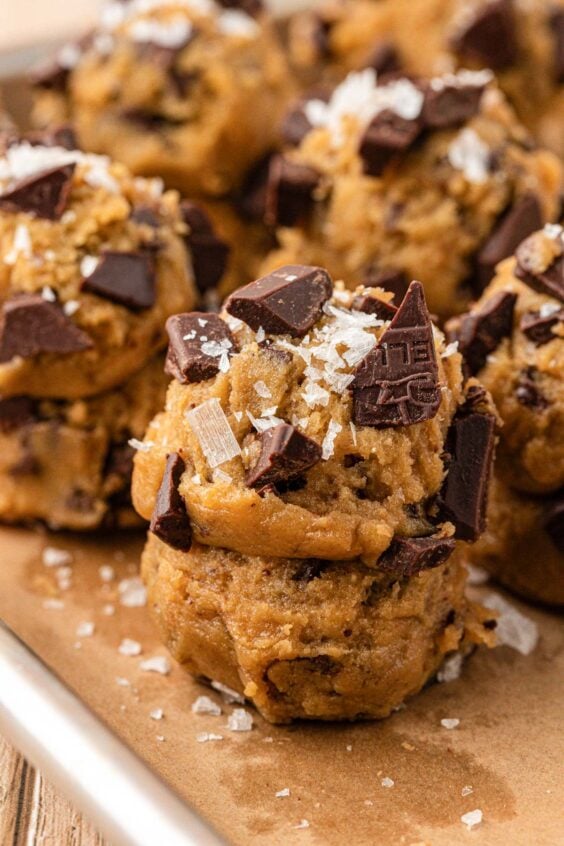 Stacked scoops of cookie dough on a parchment lined baking sheet.