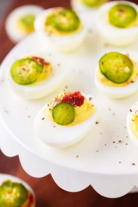 Spicy Deviled Eggs with bacon and jalapeno on white plate.