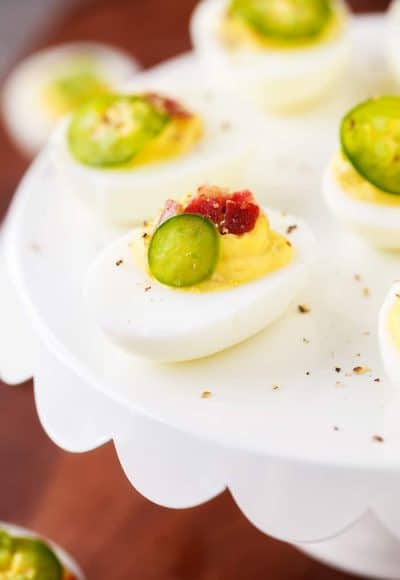 Spicy Deviled Eggs are made with mayo, mustard, relish, sriracha, jalapeño, and bacon. This easy recipe is the perfect snack to serve at summertime barbecues and cookouts!