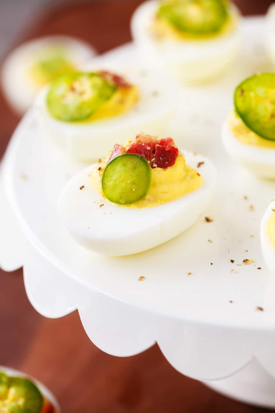 Spicy Deviled Eggs are made with mayo, mustard, relish, sriracha, jalapeño, and bacon. This easy recipe is the perfect snack to serve at summertime barbecues and cookouts!