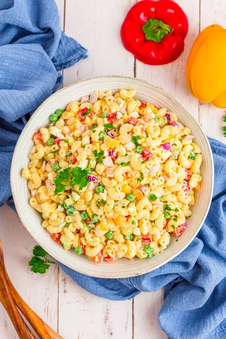 Overhead photo of a large bowl of macaroni salad on a white wooden table.