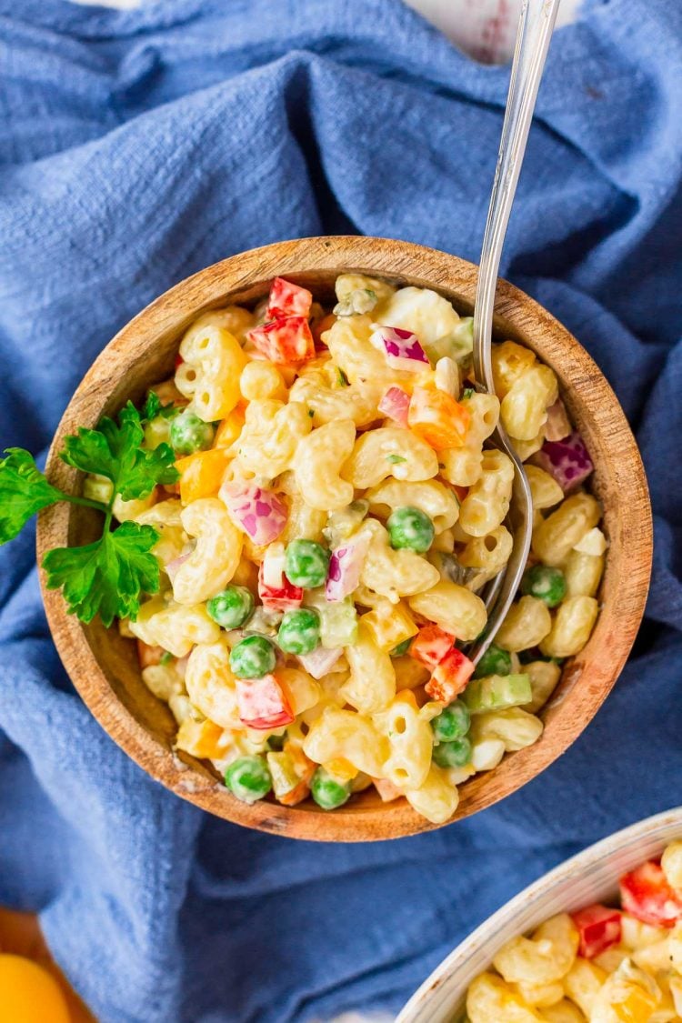 A wooden bowl filled with macaroni pasta salad on a blue napkin.