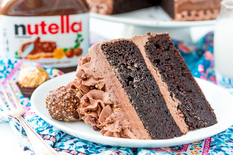 A slice of nutella cake on a white plate with a fork next to it.