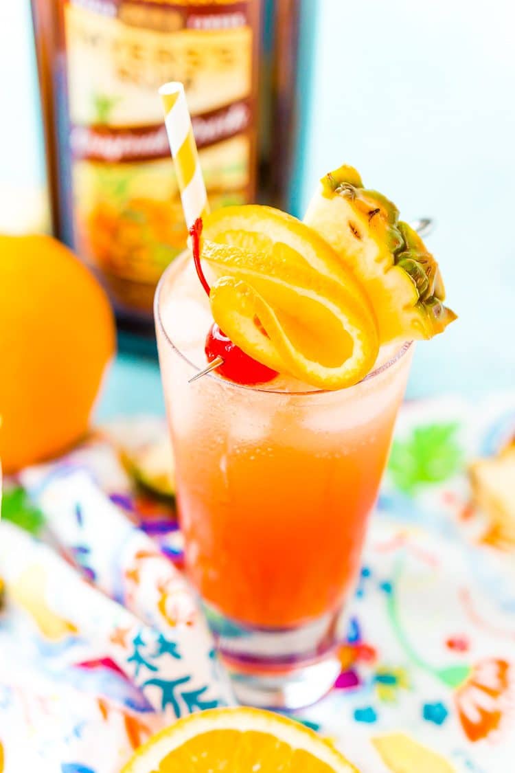 Close up photo of a glass of planters punch garnished with maraschino cherry, pineapple wedge, and orange slice.