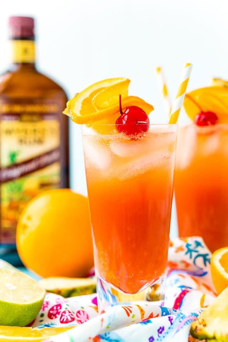 Two glasses filled with planter's punch with a bottle of rum in the background.