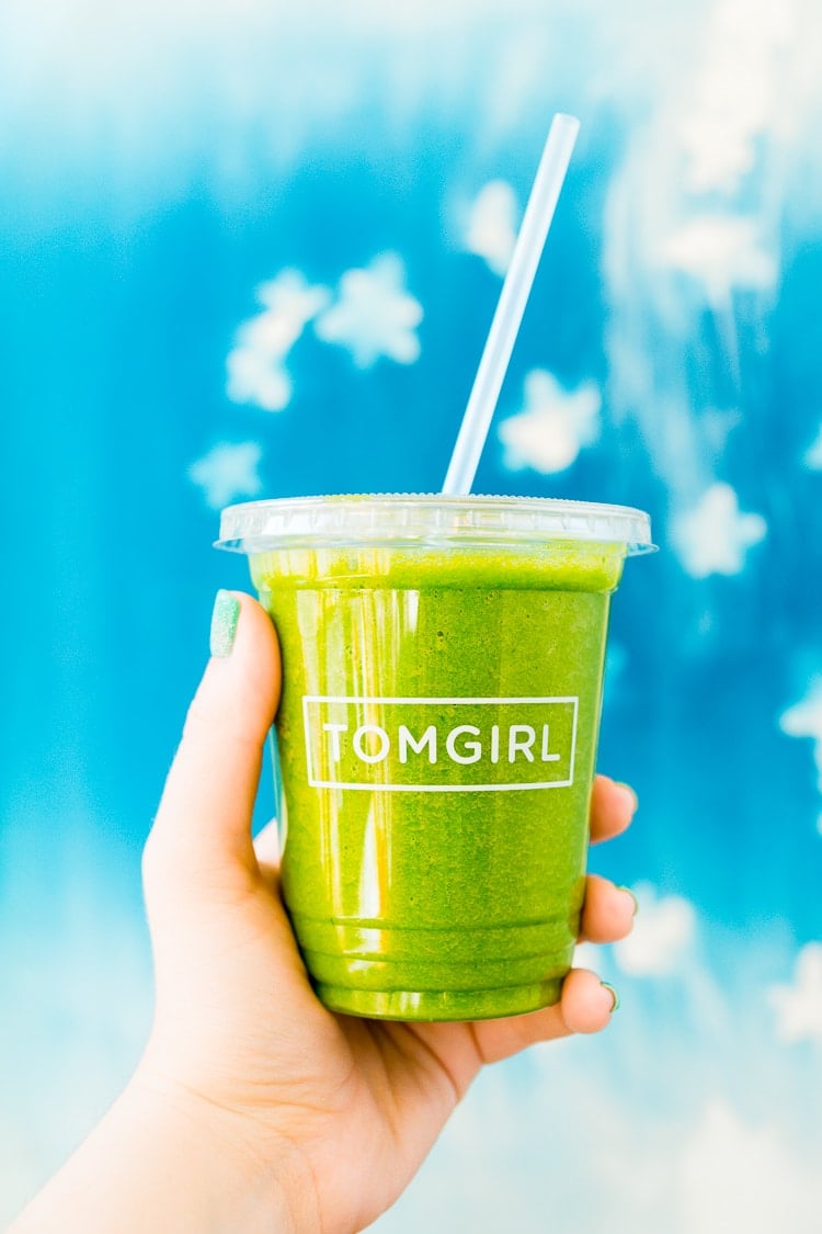 A hand holding a to-go cup from TOMGIRL