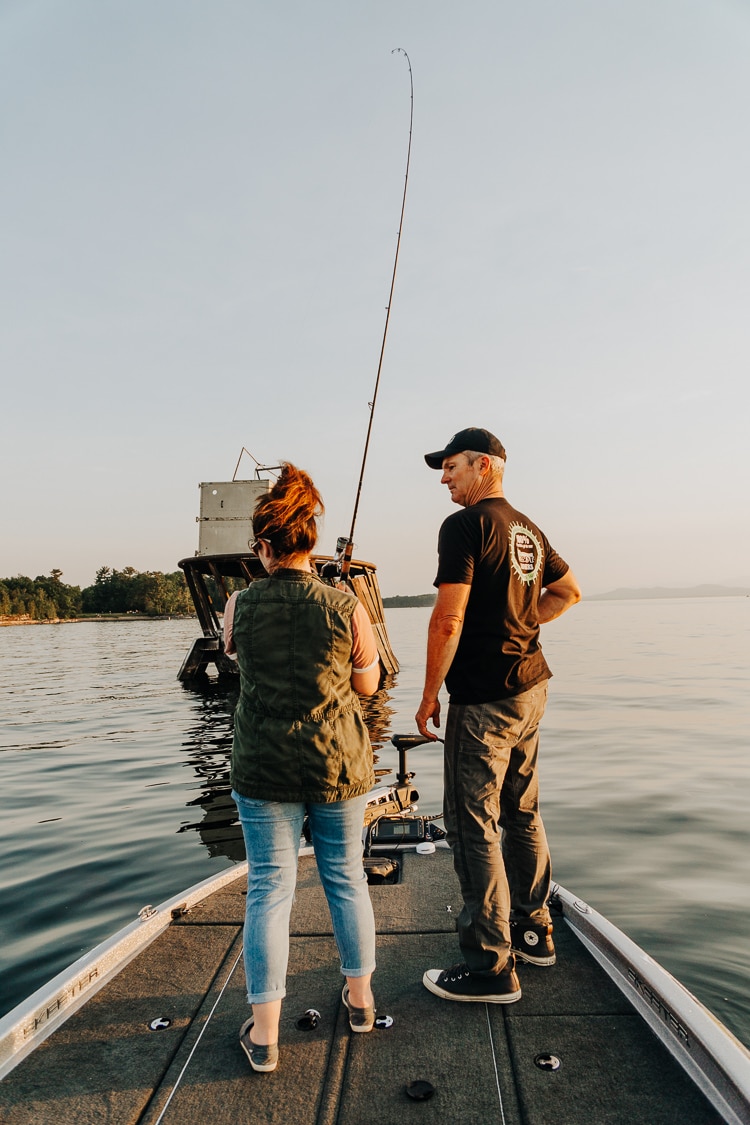 Rebecca casting a fishing rod, standing on a boat with a guide.