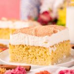 Close up photo of a slice of tres leche cake on a white plate.