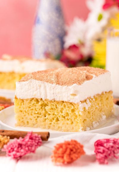 Close up photo of a slice of tres leche cake on a white plate.