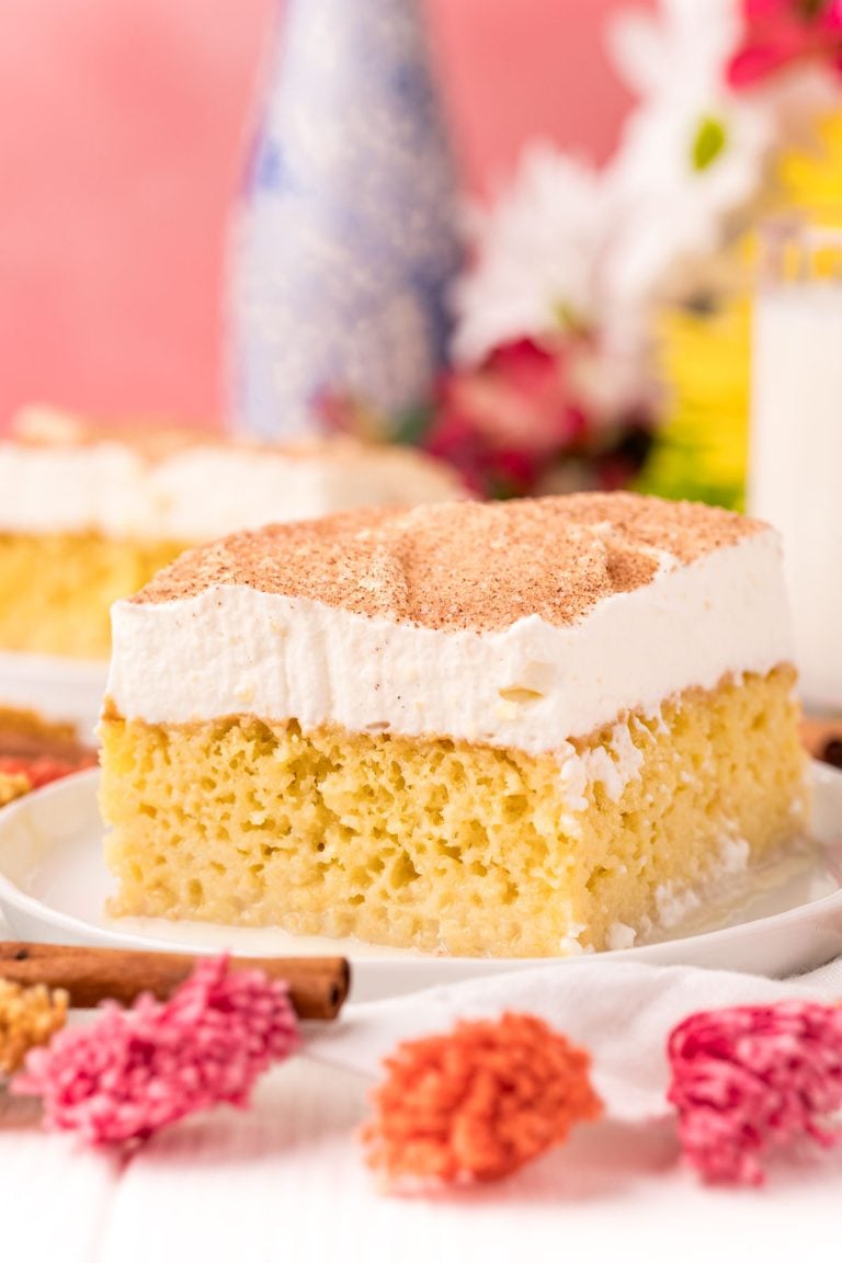 Close up photo of a slice of tres leche cake on a white plate.