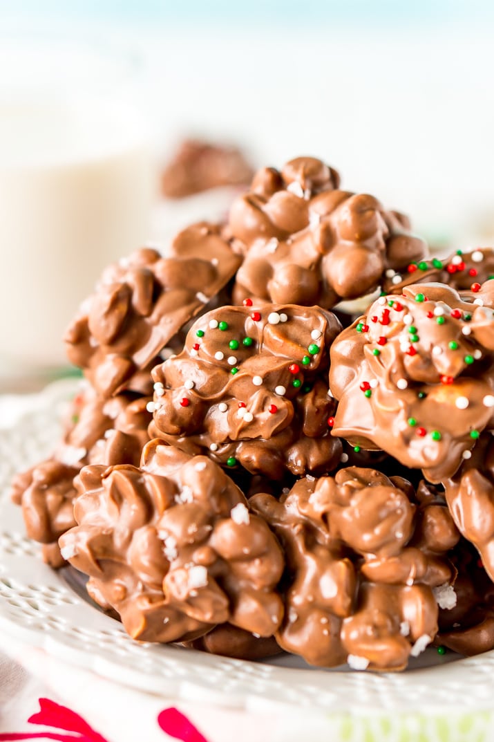 Crockpot Candy is loaded with peanuts, almond bark, and lots of chocolate and super easy to make in the slow cooker! Topped with some festive sprinkles, this pop-in-your-mouth treat is perfect for sharing during the holiday season.