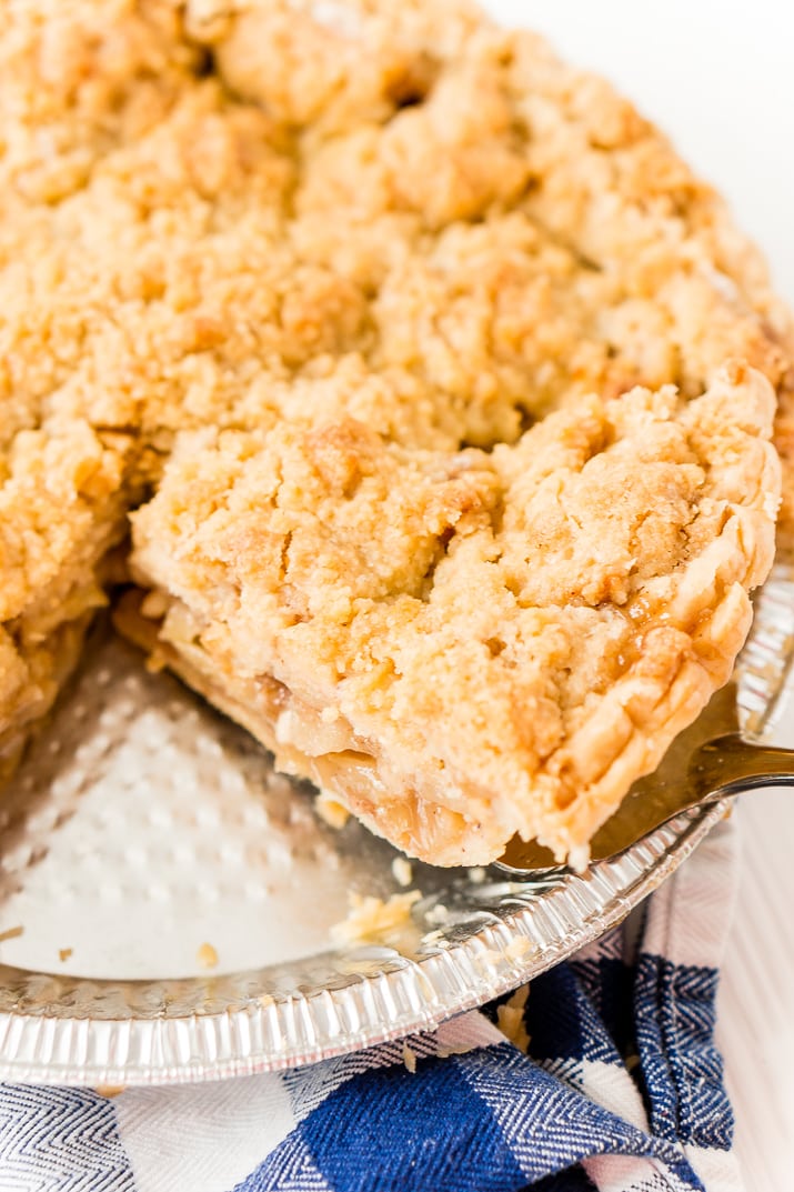 Dutch apple pie slices being taken out of the pie pan.