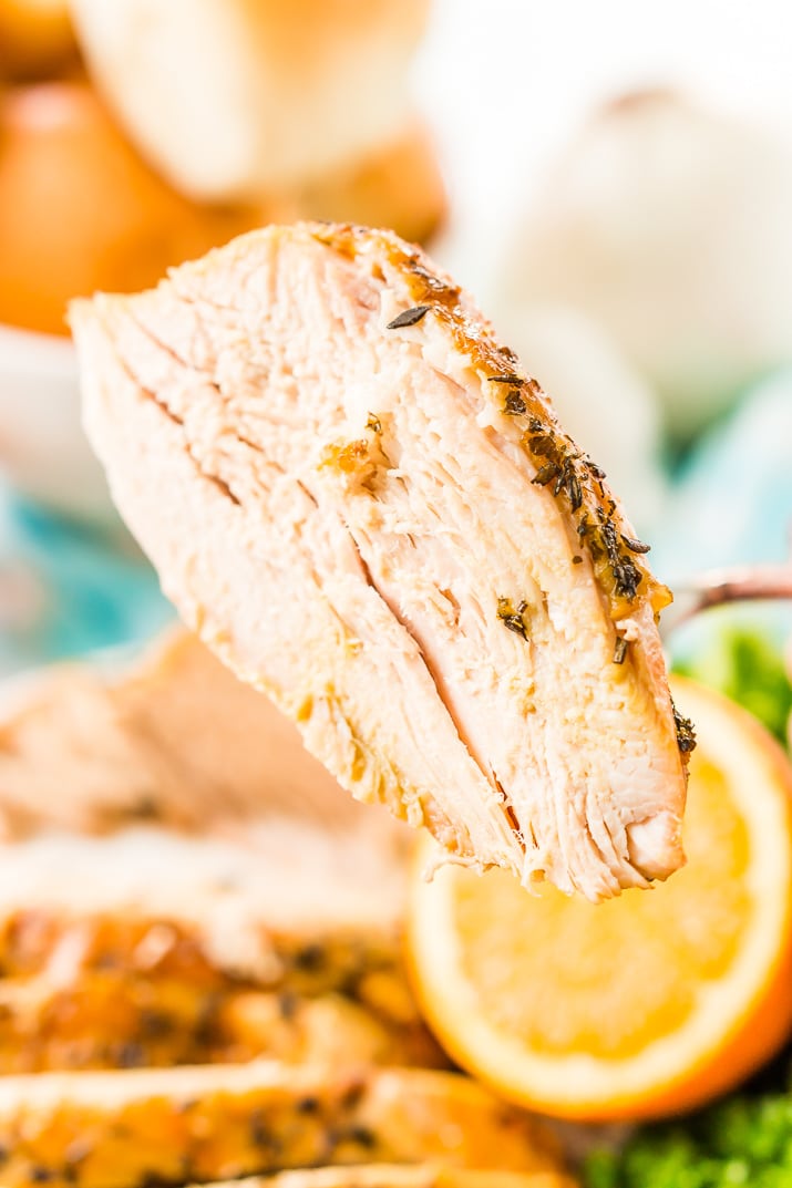 Big slice of turkey breast being held with a fork.