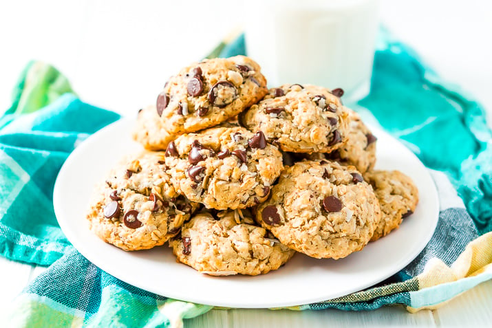 Lactation Cookies on a white plate on a blue and green napkin with a glass of milk in the background.