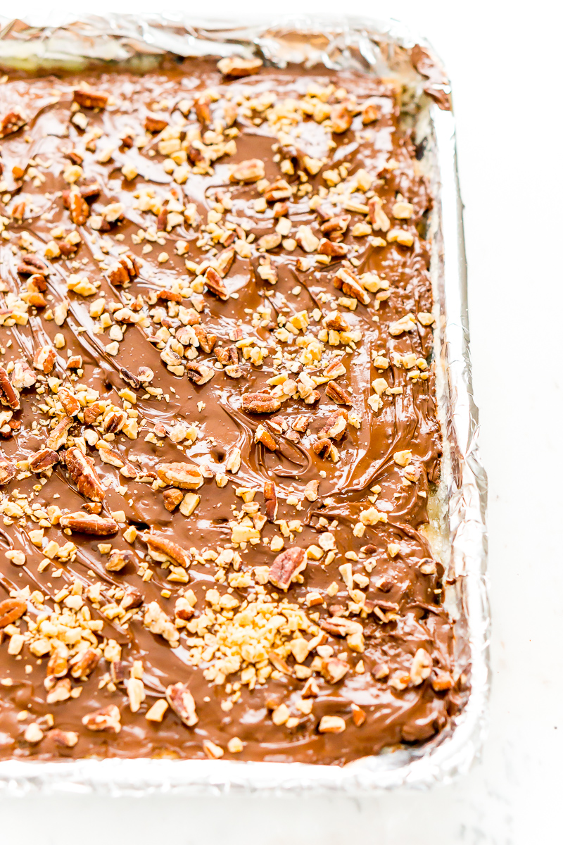 Chocolate and nuts on shortbread cookies on foil lined pan.