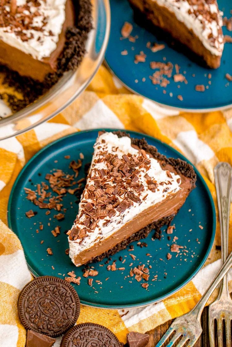 slices of chocolate cream pies on blue plates on yellow checkered napkins.