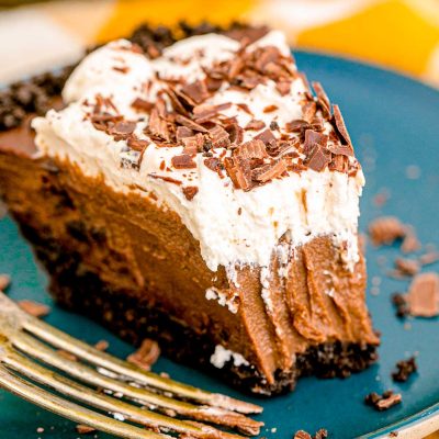 A slice of chocolate cream pie on a blue plate with a bite missing from it.