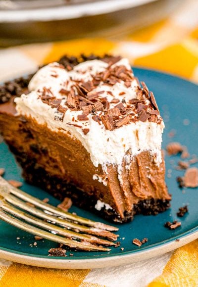 A slice of chocolate cream pie on a blue plate with a bite missing from it.