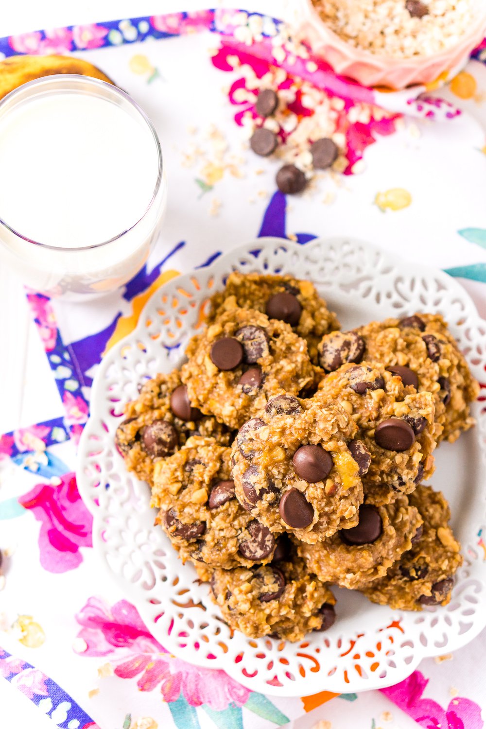 Overhead shot of Banana Chocolate Chip Cookies on white plate with glass of milk.