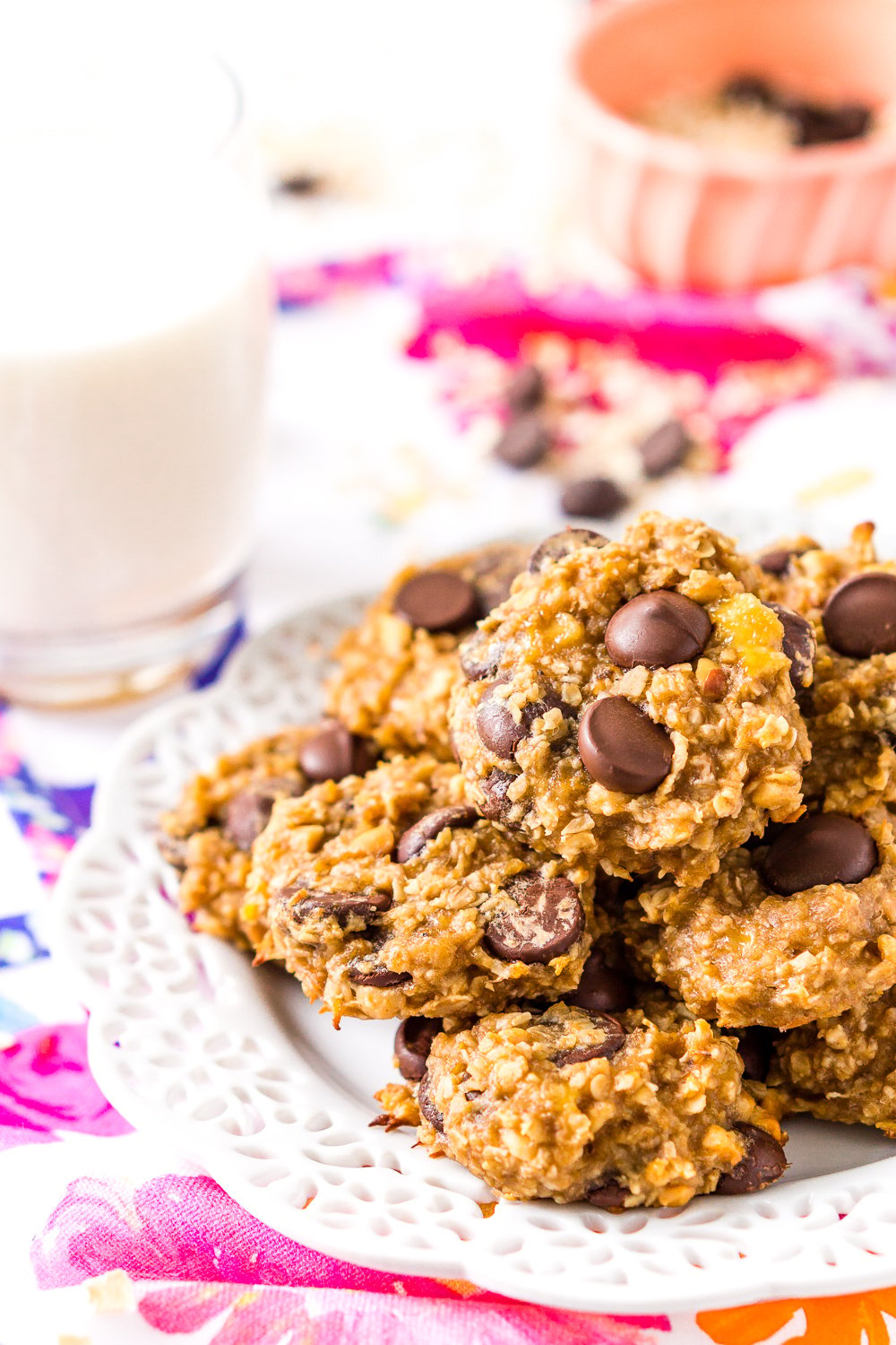 Banana Oatmeal Cookies on white plate on colorful napkin with glass of milk and pink bowl in background