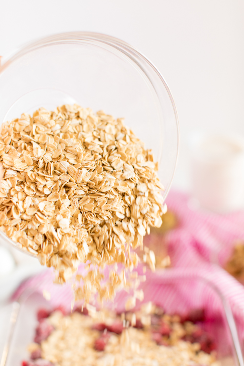 Oatmeal pouring over raspberries in a baking dish to make baked oatmeal.