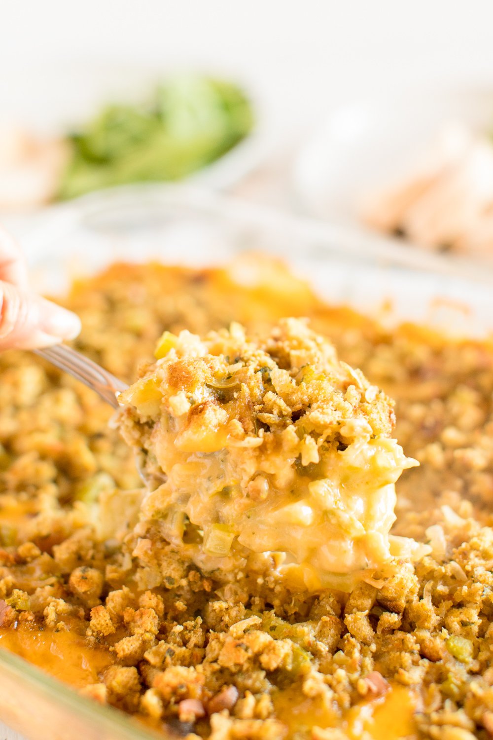 A serving spoon scooping broccoli casserole out of a pan.