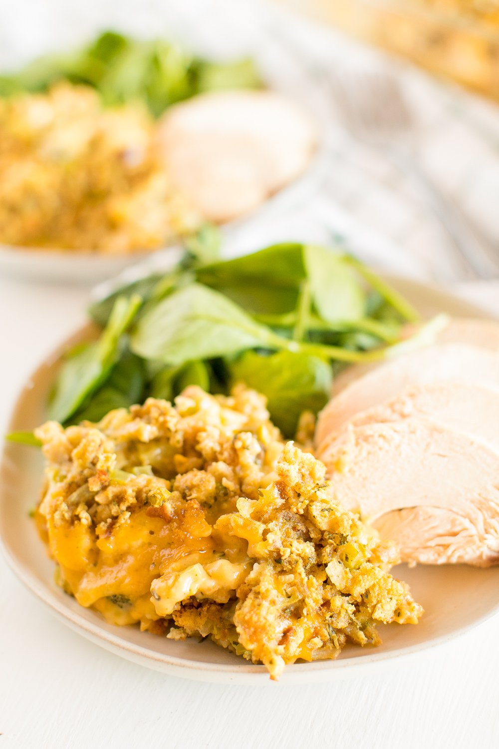 Plate with Broccoli Cheese Casserole, chicken breast, and salad on it.