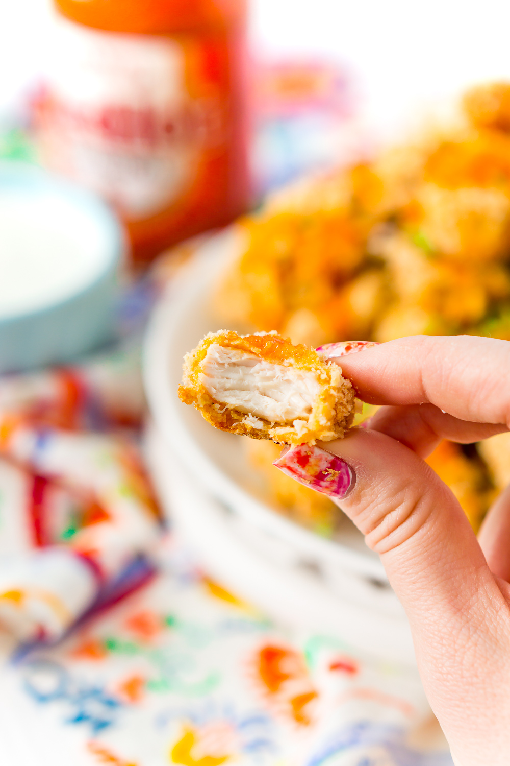 A Crispy Baked Chicken Wing bitten into being held by a woman's hand.