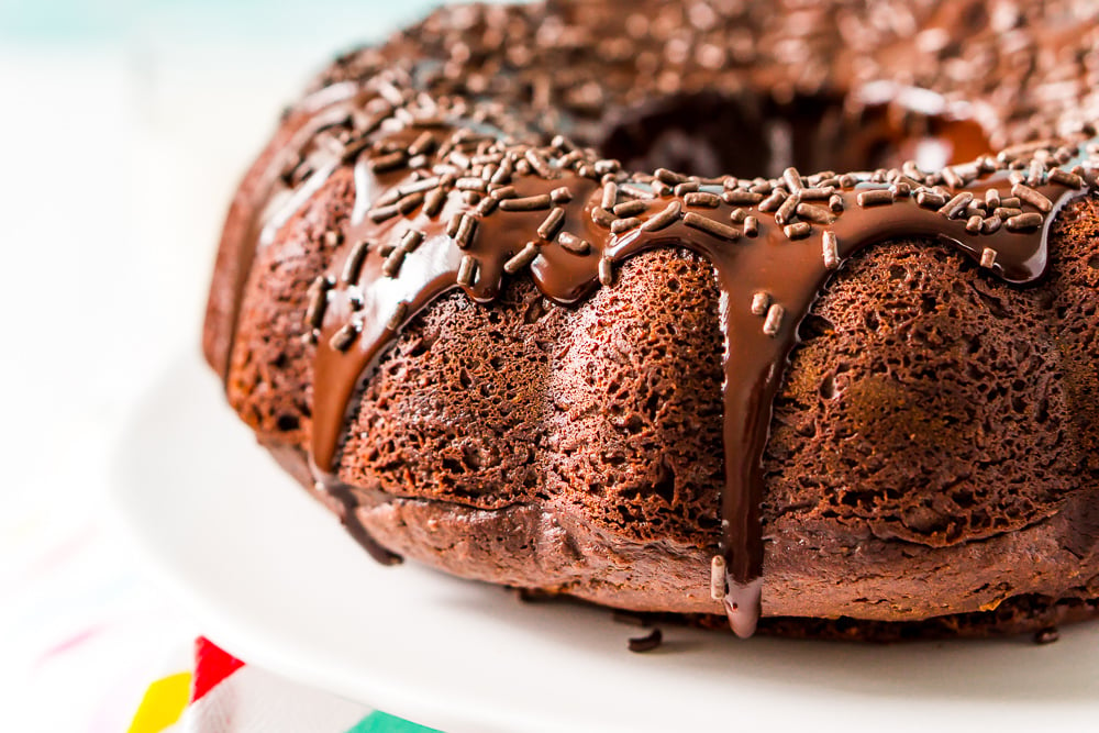 Close up of healthier chocolate bundt cake made with applesauce and yogurt. Topped with a faux chocolate ganache and chocolate sprinkles.