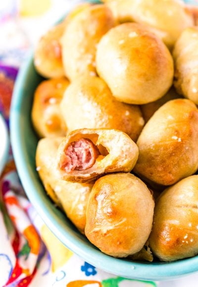 These Pretzel Pigs In A Blanket take two of your favorite party foods and combine them into one! Mini sausages and cheddar cheese wrapped in dough and baked to perfection!