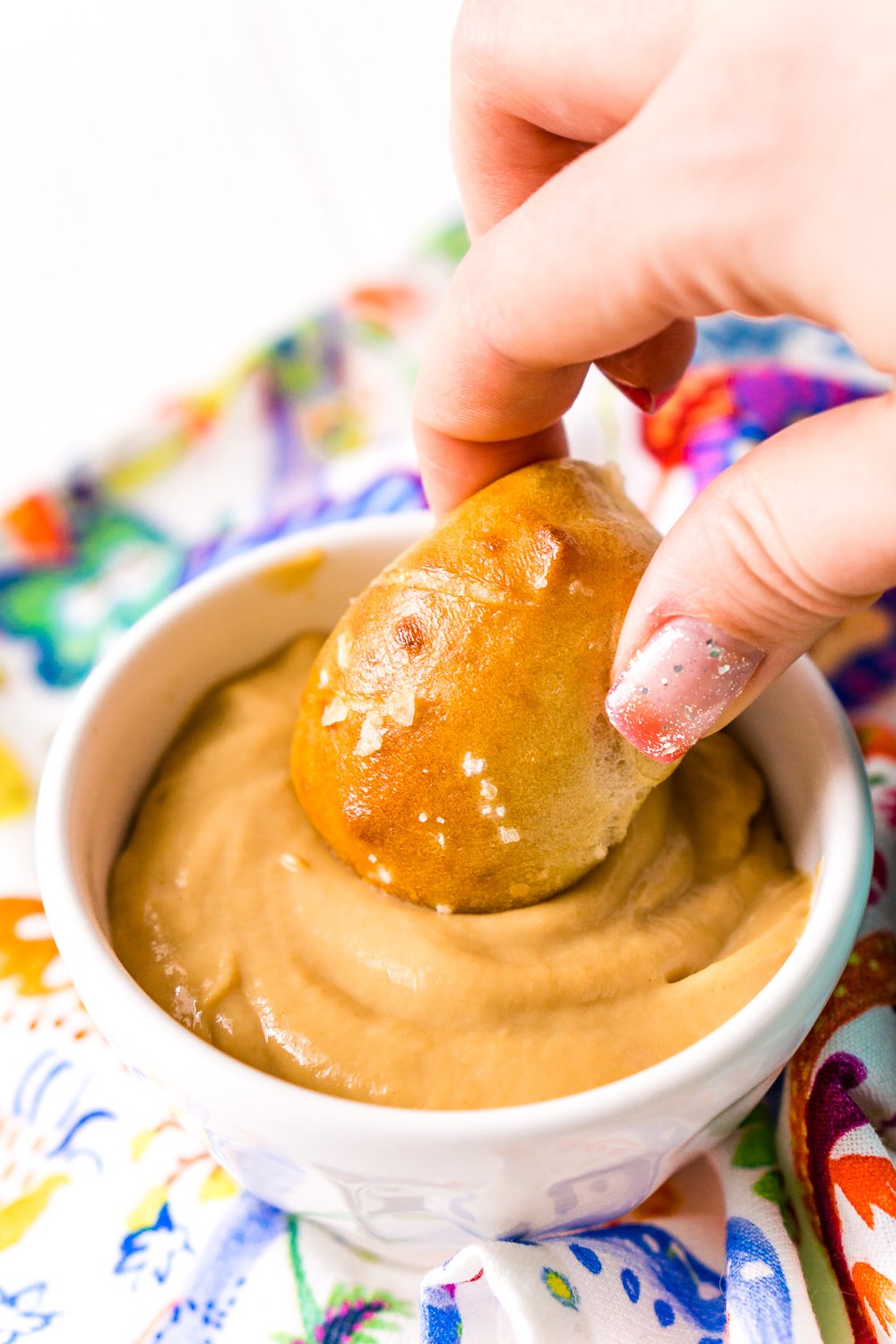 Woman's hand dipping pigs in a blanket into dipping sauce.