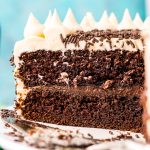 Chocolate Guinness Cake that's been sliced into and you can see the layers of chocolate cake, chocolate ganache, and Irish Cream Buttercream against a blue background.