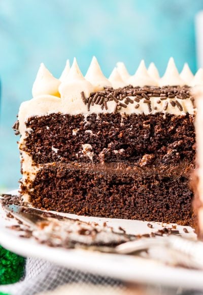 Chocolate Guinness Cake that's been sliced into and you can see the layers of chocolate cake, chocolate ganache, and Irish Cream Buttercream against a blue background.