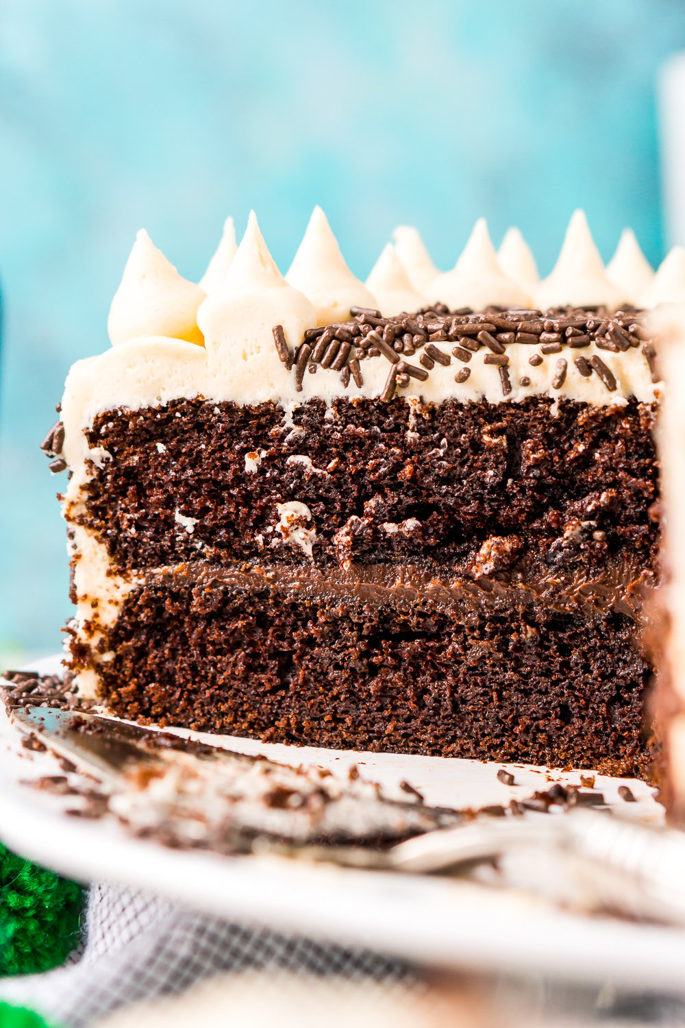 Chocolate Guinness Cake that's been sliced into and you can see the layers of chocolate cake, chocolate ganache, and Irish Cream Buttercream against a blue background.