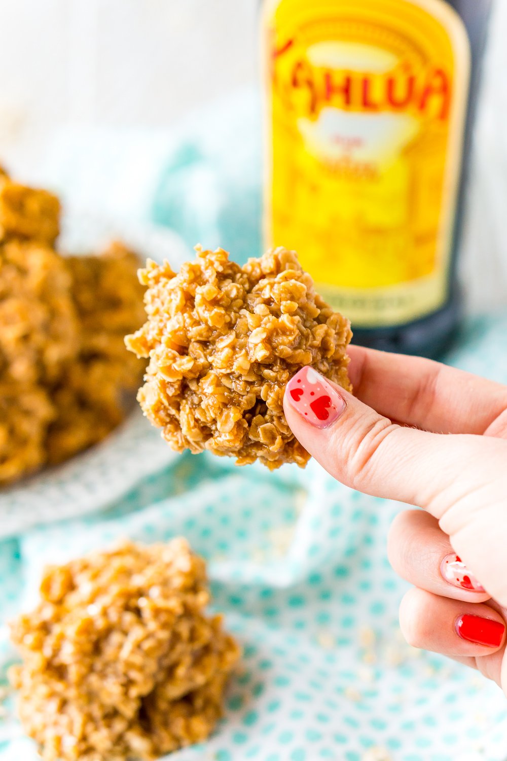 Woman's hand holding a Kahlua No Bake Cookie with bottle of Kahlua in the background.