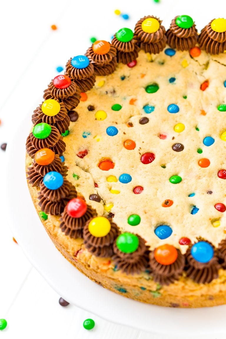 This M&M's Cookie Cake Recipe is a fun and easy dessert recipe the whole family will enjoy. A giant cookie made with M&M's and chocolate frosting for even more deliciousness!