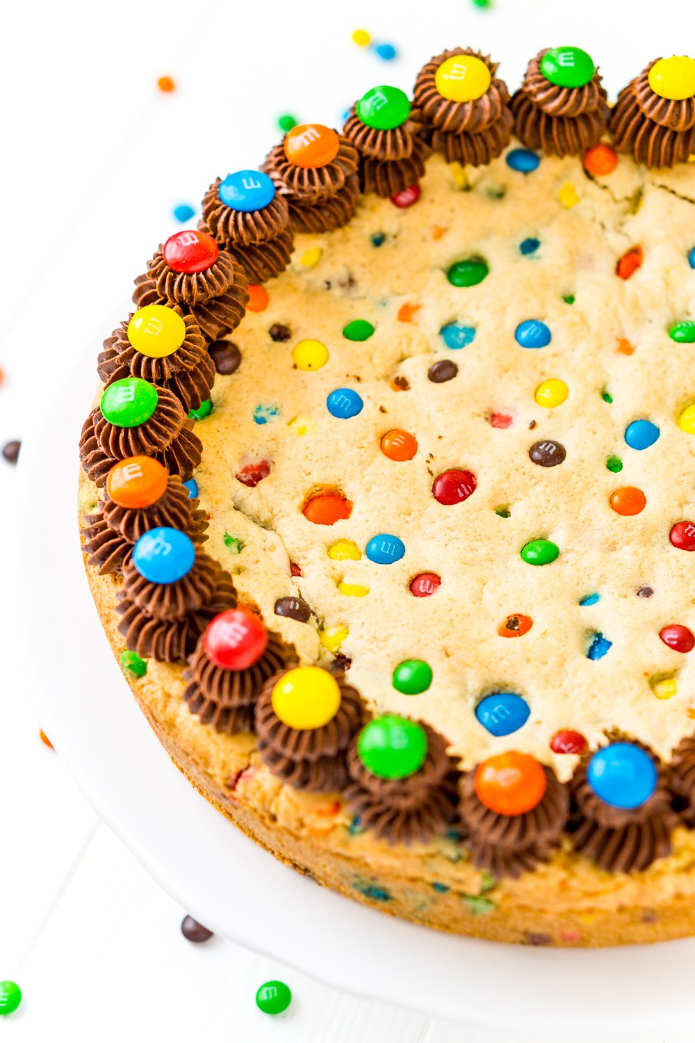 Close up of whole Cookie Cake with M&M's and chocolate frosting.