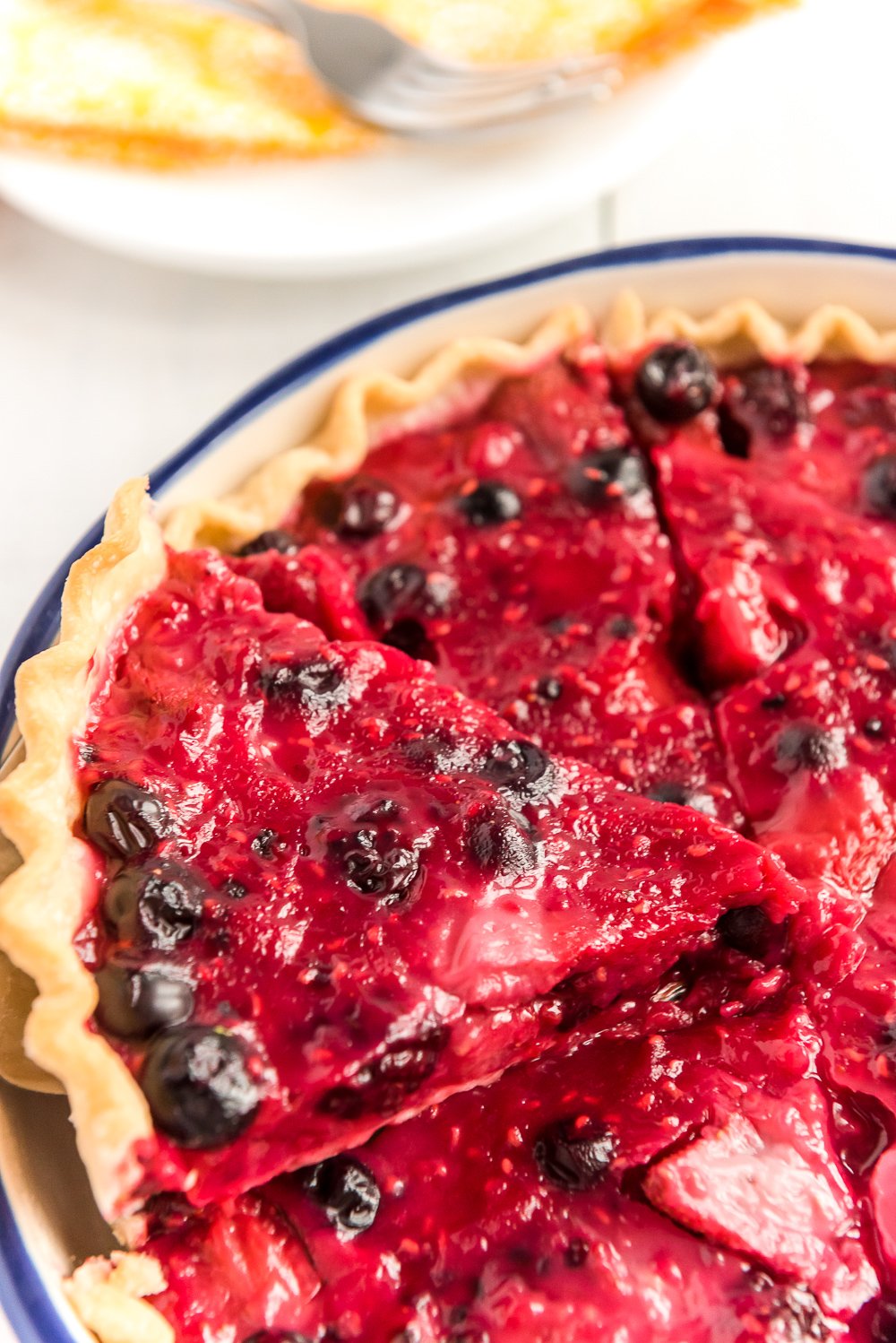 Slice of Mixed Berry Pie being pulled from a whole pie.