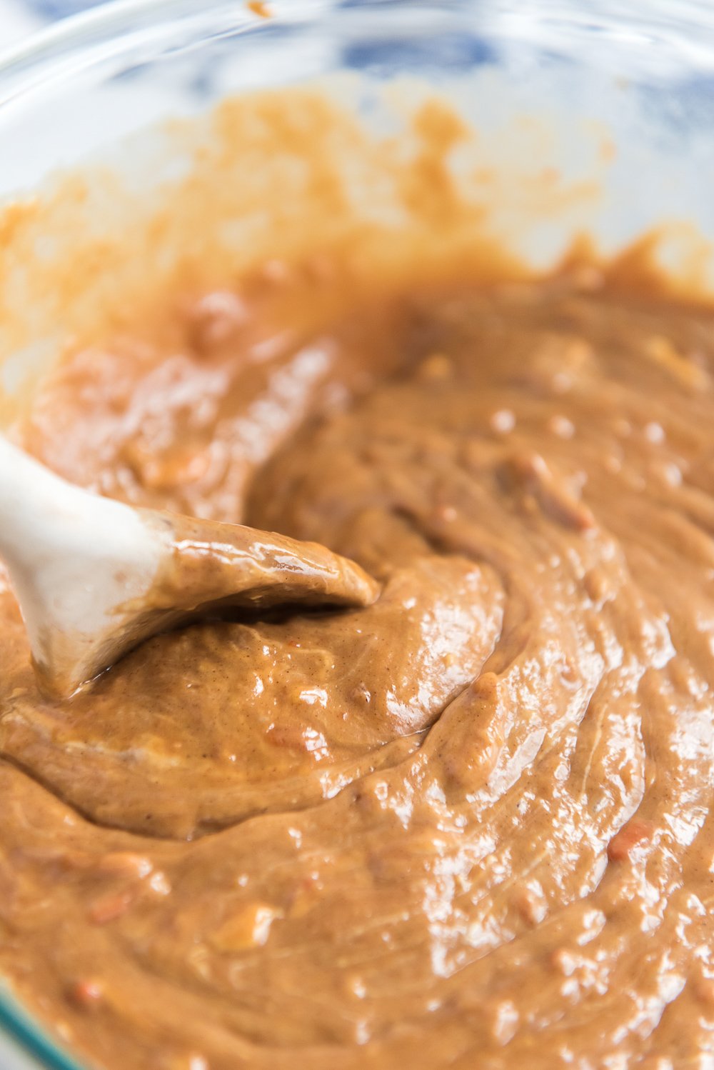 Batter for Caramel Carrot Cake in a bowl with a white mixing spoon.