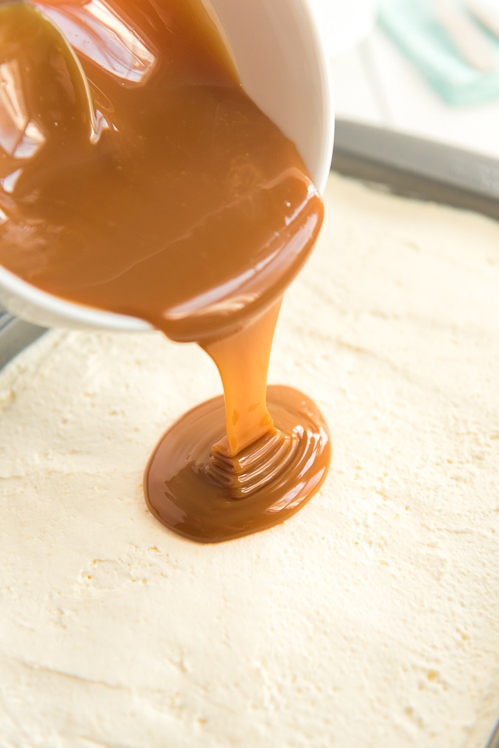 Caramel being poured over a frosted Carrot Cake.