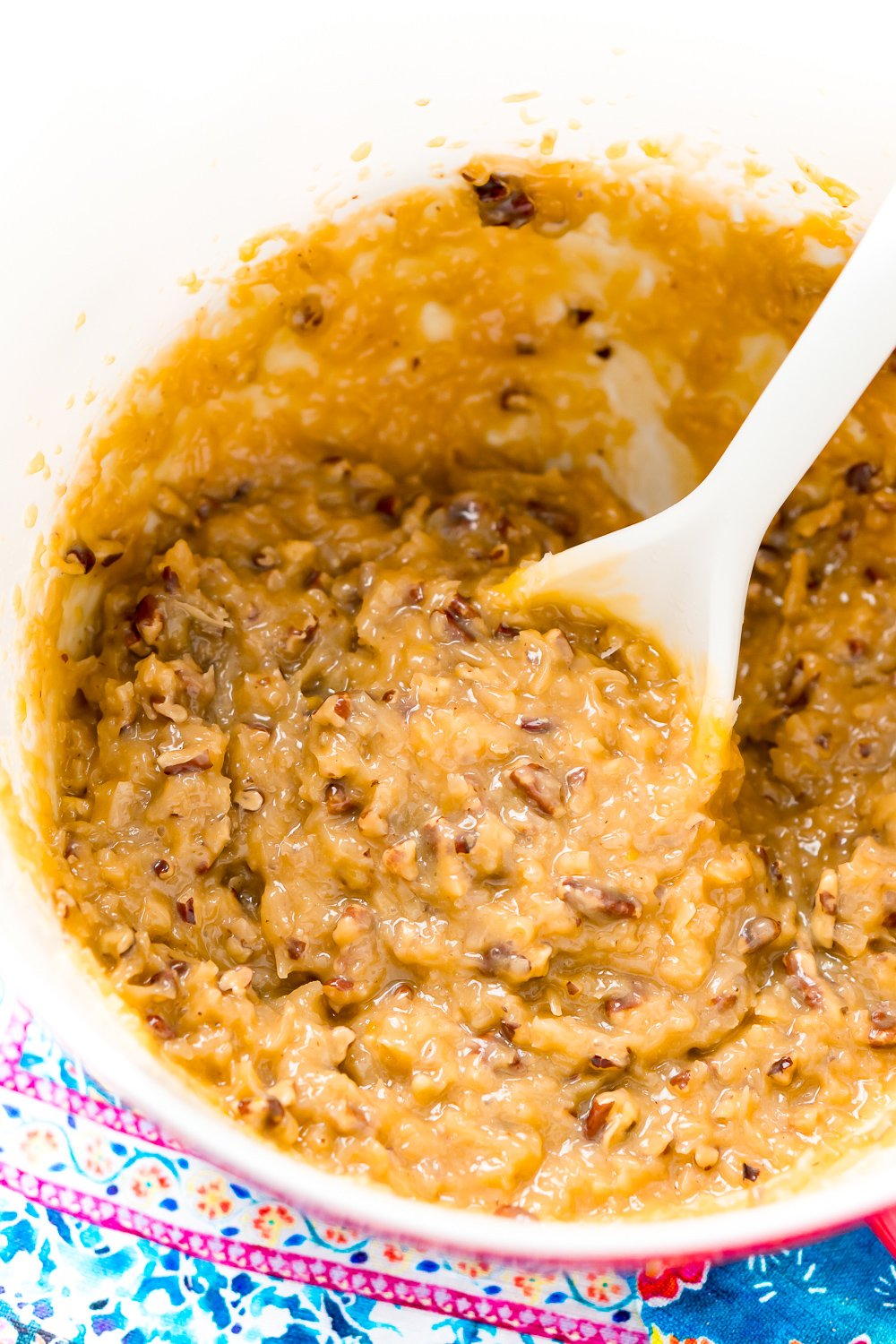 Coconut Pecan Frosting in a large mixing bowl with a white spoon.