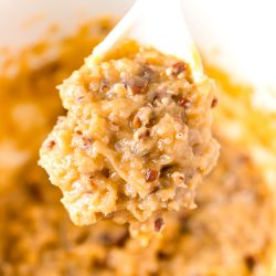 White mixing spoon full of Caramel Pecan Frosting above a bowl of more frosting.