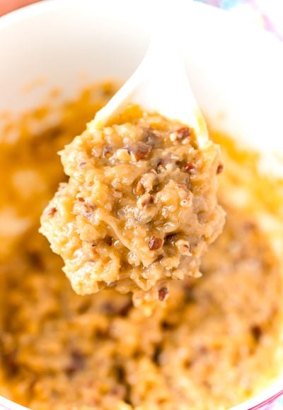 White mixing spoon full of Caramel Pecan Frosting above a bowl of more frosting.