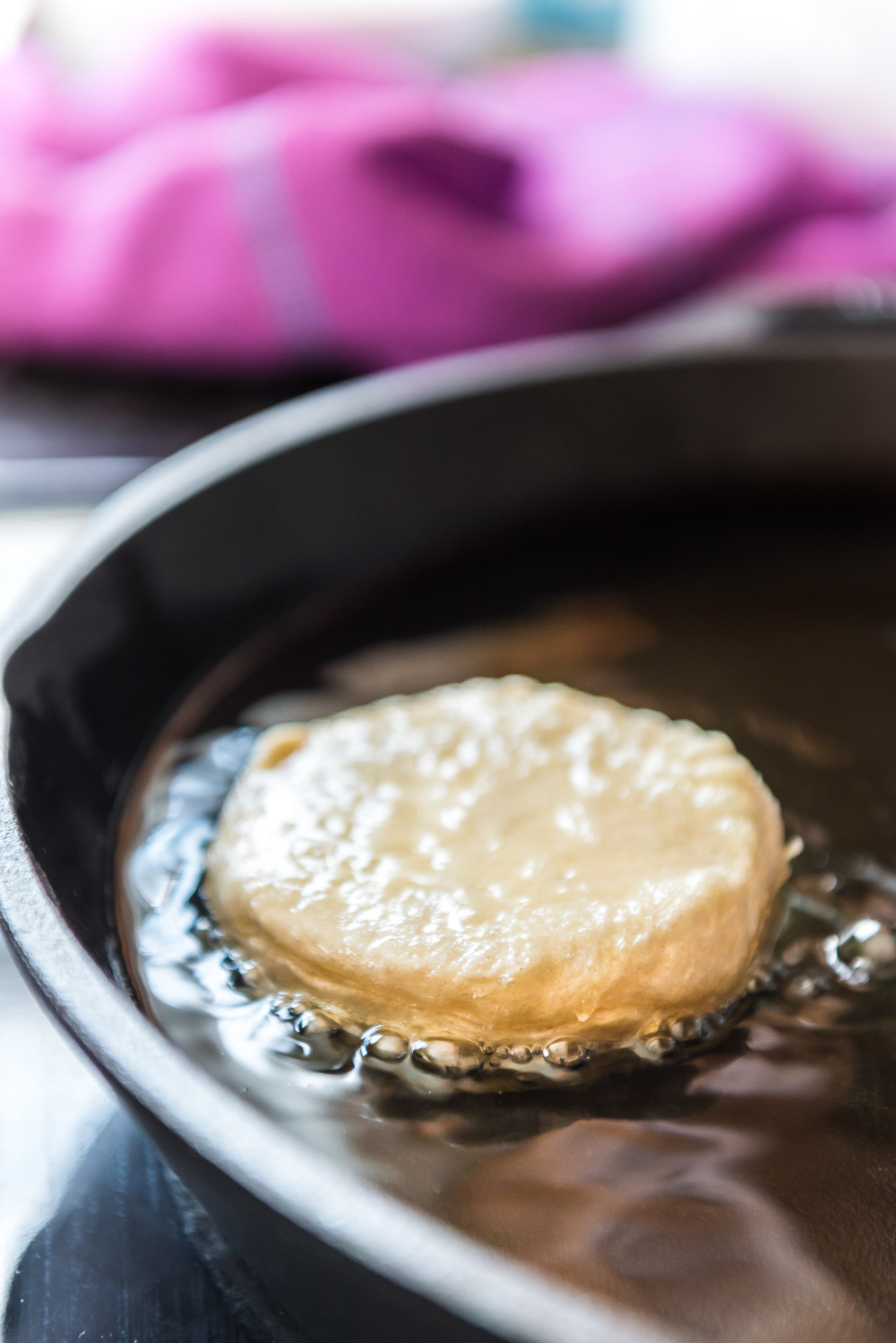 Refrigerated biscuit being fried in a cast iron panto make donuts.