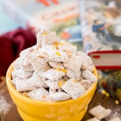 Butterbeer muddy buddies in a yellow bowl with Harry Potter books in the background.